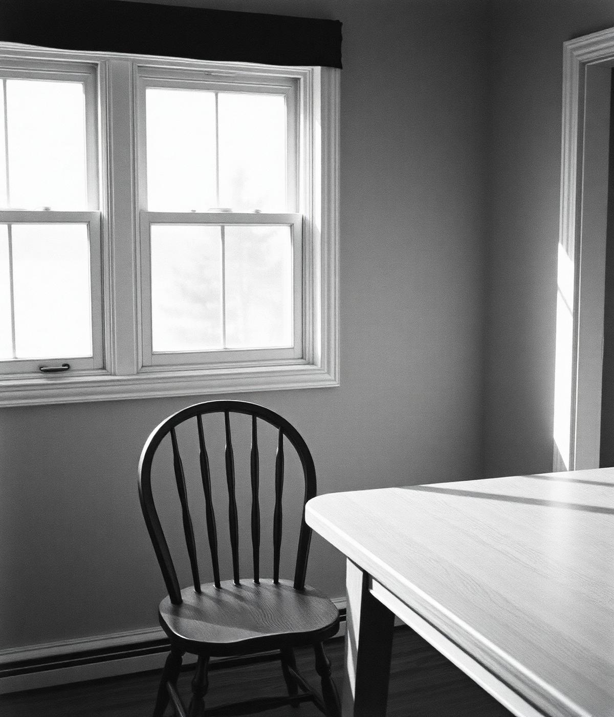 An empty chair at a kitchen table by a sunny window